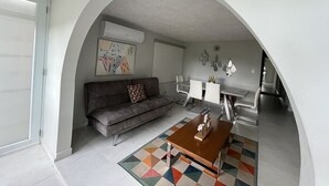 A modern living room with a sofa, coffee table, and dining area under an arched ceiling. - Villa Teresa1, equipped with solar panels,water cistern, air conditioner, WiFi  (Carolina)