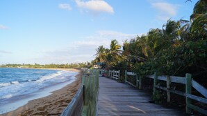 A wooden boardwalk along a beach with palm trees and ocean waves. - Villa Teresa1, equipped with solar panels,water cistern, air conditioner, WiFi  (Carolina)