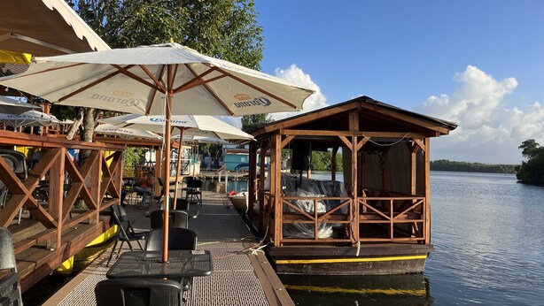 A wooden dock with seating and umbrellas, a covered area with a speaker, and a view of the water. - Villa Teresa1, equipped with solar panels,water cistern, air conditioner, WiFi  (Carolina)