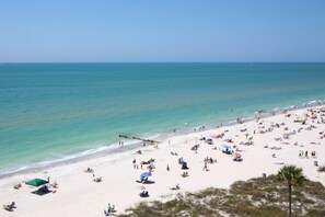 A beach with people sunbathing and swimming.