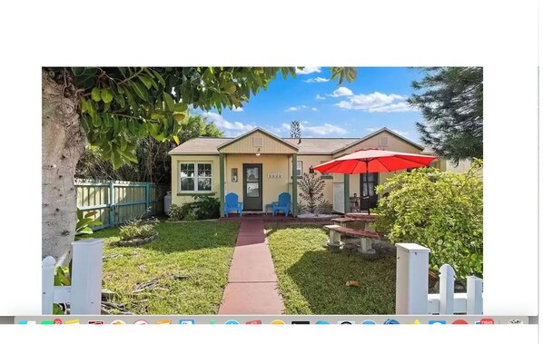 A single-story house with a front porch, a red umbrella, and a small garden.