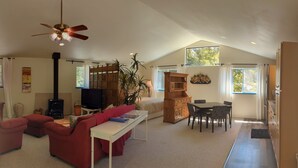 A cozy living room with a red sofa, a white table, a TV, and a fireplace. - Asian-themed Queen's Loft Apartment 10 mins to the beach and downtown! (GUALALA)