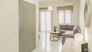 A modern living room with a sofa, a round coffee table, and a lamp. - Fully renovated apartment in the city centre of Chania with a roof garden! (Χανιά)