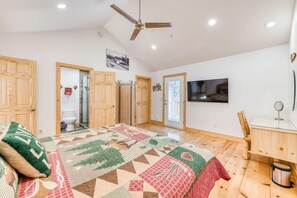 Ein Schlafzimmer mit einem großen Bett, einem Holzschrank, einem Deckenventilator und einem an der Wand befestigten Fernseher.