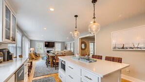 Una cocina moderna con armarios blancos, una isla central e iluminación colgante.