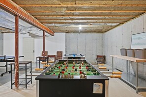 A room with a foosball table, chairs, and a ping pong table. - Chatham Luxury Retreat—Porch, Art & Family Fun (Chatham)