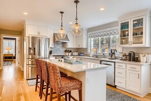 A modern kitchen with a central island, stainless steel appliances, and a large window providing natural light.