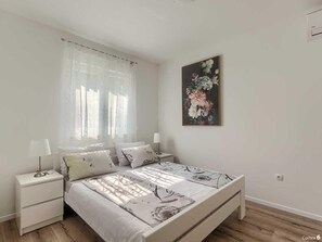 A bedroom with a bed, nightstands, a lamp, and a floral painting on the wall. - 3 BD Villa with Private pool, surrounded by greenery (Buje)