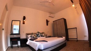 Een slaapkamer met een bed, een bureau, een kledingkast en een plafondventilator.