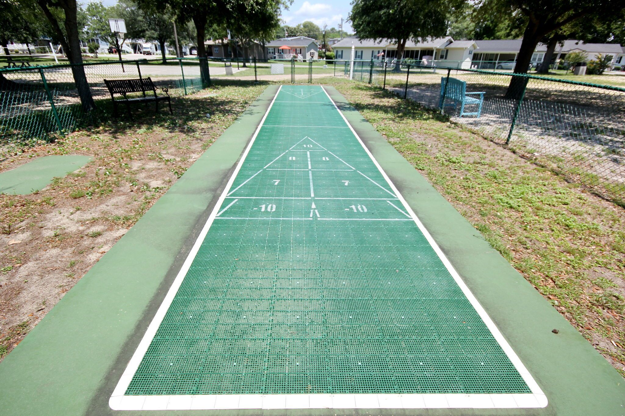 A green shuffleboard court with a white boundary line and numbered scoring areas.