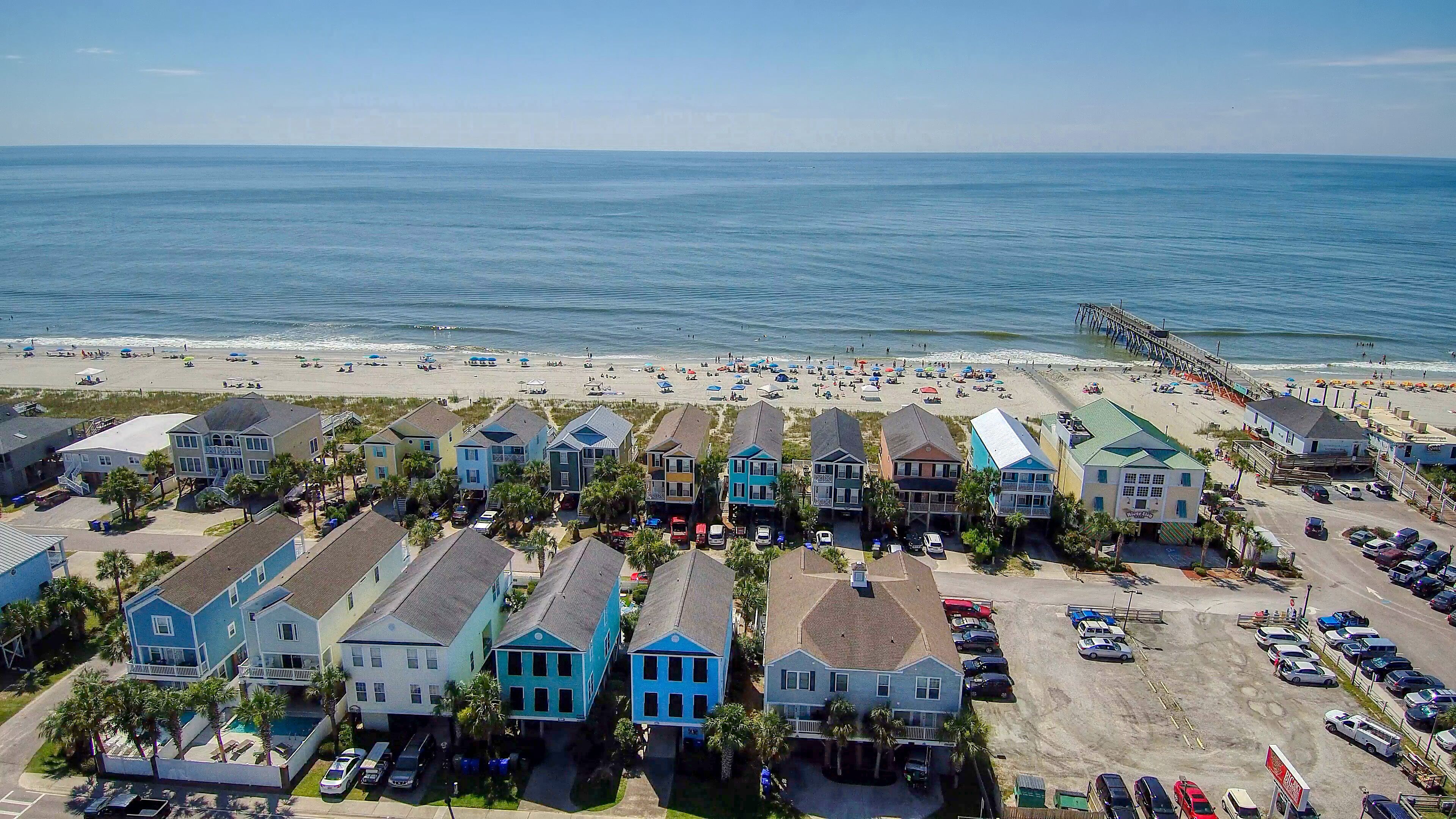 A coastal residential area with beachfront properties, a pier, and a beach with umbrellas.