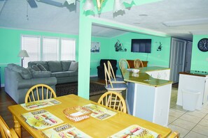 Un espace repas avec une table en bois, des chaises et une cuisine en arrière-plan.