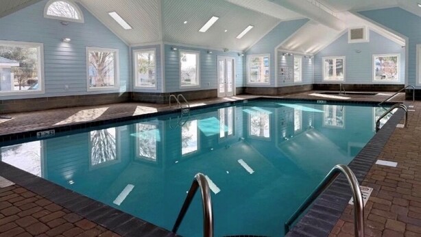 En inomhuspool med kristallklart blått vatten, omgiven av fönster och ett kaklat golv.
