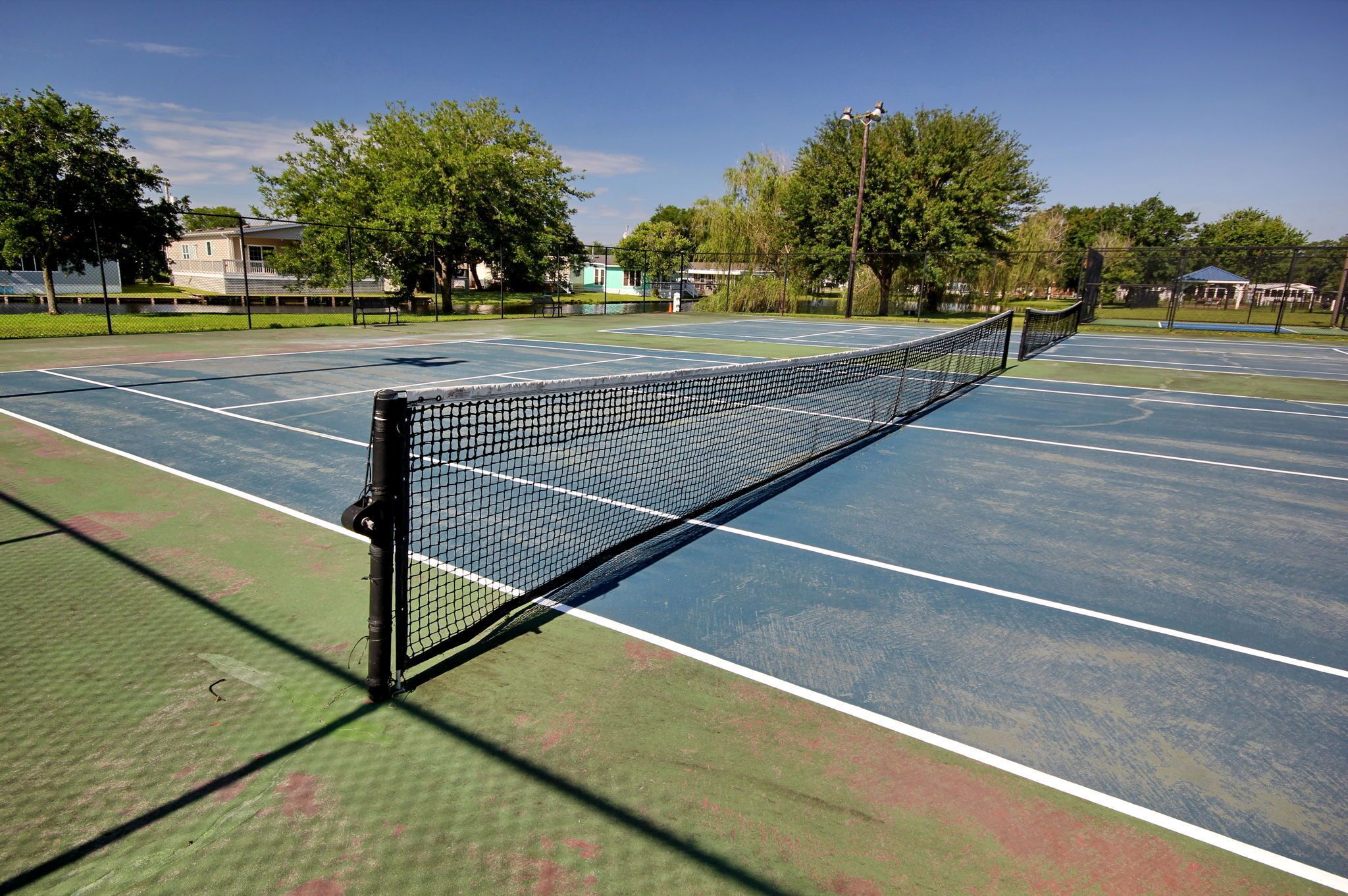A tennis court with a net, surrounded by trees and buildings.