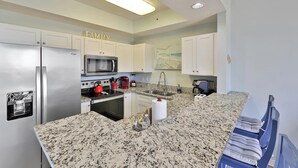 Una cocina moderna con encimeras de granito, electrodomésticos de acero inoxidable y un letrero en la pared que dice 'FAMILIA'.
