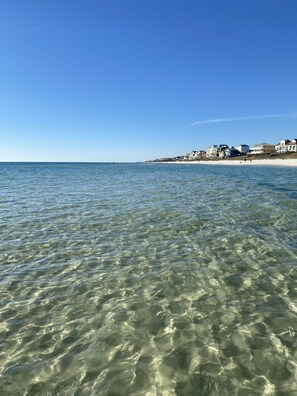 Clear shallow waters of a beach with a row of houses in the background. - Beautiful new contemporary beach house less than 10 walking minutes to the beach (Inlet Beach)