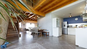A spacious kitchen with modern appliances, a dining area with a wooden table and chairs, and a staircase leading to an upper level. - Charming 9-person gîte with heated swimming pool (Peyrusse-Grande)