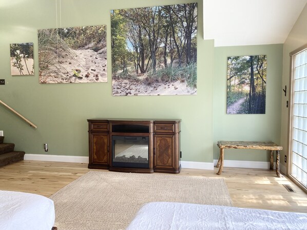 A bedroom with a bed, a wooden dresser, and three framed pictures on the wall.