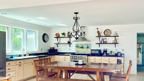 A modern kitchen with wooden cabinets, a dining table, and a chandelier.