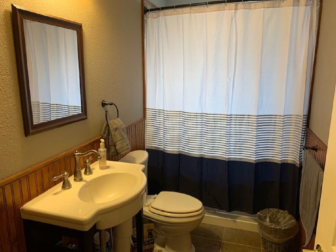 A bathroom with a sink, toilet, and shower curtain.