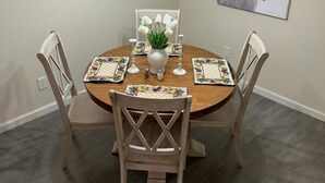 A dining area with a round wooden table, four chairs, a chandelier, a vase with flowers, and a framed picture on the wall. - 2 bedroom, 2 bath farmhouse (Blythe)