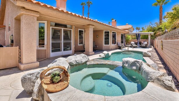 Une maison avec une piscine, du mobilier de jardin et des palmiers.