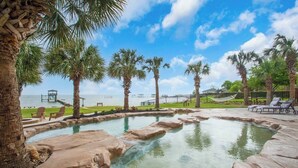 A pool with rock formations, palm trees, and a view of the ocean. - Luxury Waterfront Estate w/ Heated Pools, Private Pier & Walk to Boardwalk (Kemah)