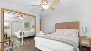 A hotel room with a large bed, a ceiling fan, a mirror, and a view of the outdoors. - Luxury Waterfront Estate w/ Heated Pools, Private Pier & Walk to Boardwalk (Kemah)