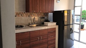Eine moderne Küche mit Holzausstattung, einem Edelstahlkühlschrank und einer gefliesten Spritzschutzwand.