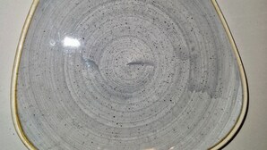 A ceramic plate with a speckled design and a yellow rim, placed on a flat surface.