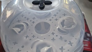 A white plastic cover with a lid, featuring a cross-shaped handle and decorative cutouts.