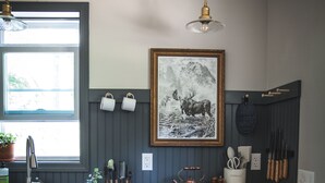A kitchen with a black refrigerator, wooden countertop, hanging light fixture, and a framed picture on the wall. - A Family Glamping Adventure Awaits (Victor)
