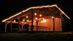 A wooden pavilion with a covered picnic area, benches, and a table.