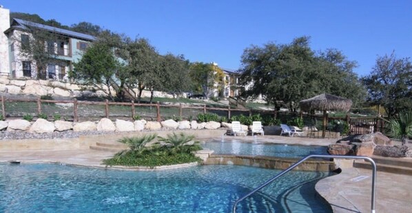 Relax by the tranquil pool, surrounded by lush trees and a natural landscape.