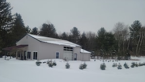 A single-story house with a garage, surrounded by snow-covered ground and trees.