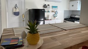 A kitchen with a wooden countertop, a black refrigerator, and a white wall-mounted air conditioner. - Foothills casita 1 Bedroom (El Paso)