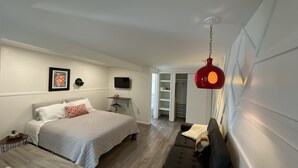 A modern bedroom with a bed, a TV, a red hanging light, and a wardrobe. - Foothills casita 1 Bedroom (El Paso)