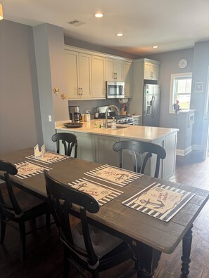 A modern kitchen with light gray cabinets, stainless steel appliances, and a central island.