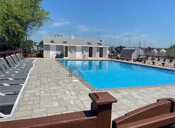 A swimming pool with lounge chairs and a building in the background.