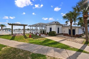A residential area with a covered patio, a white house, and palm trees.