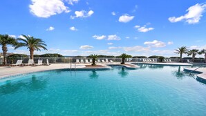 A large outdoor swimming pool with multiple lanes, surrounded by palm trees and lounge chairs. - A Wave From it All:  Condo on the Beach (Gulf Shores)