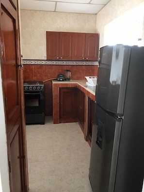 A compact kitchen with wooden cabinets, a black refrigerator, a stove, and a countertop with a blender. - 2RK-2 APARTAMENTO EN CARTAGENA CON WIFI (Cartagena)