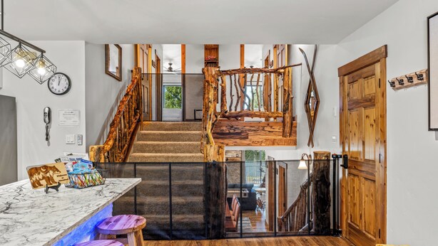 A modern interior with a wooden staircase, a marble bar with stools, and a wooden floor. - Spacious 3B/3B Condo. Luxury Amenities. ShuffleBoard. HotTubs. 1st FLR. Location (Steamboat Springs)