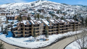 A multi-story hotel with a snow-covered landscape in the background. - Spacious 3B/3B Condo. Luxury Amenities. ShuffleBoard. HotTubs. 1st FLR. Location (Steamboat Springs)