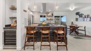 A modern kitchen with a central island, bar stools, and pendant lighting. - Soul Shine| Amazing Views | Location | Remodeled, Soul Shine| Amazing Views | Location | Remodeled (Joshua Tree)