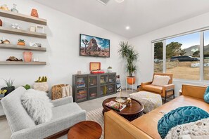 Una sala de estar moderna con un sofá, un sillón, una mesa de centro y estanterías con objetos decorativos.