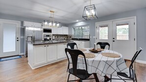A modern kitchen with white cabinetry, a central island, and pendant lighting. - Family-Friendly 4BR w/ Heated Pool, Spa & Game Room near The Woodlands and IAH (Spring)
