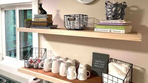 Una estantería con libros, un reloj y tazas.