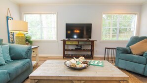 A living room with a TV, two sofas, a coffee table with decorative items, and a lamp.