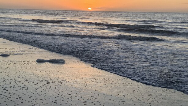 A beach with waves at sunset.